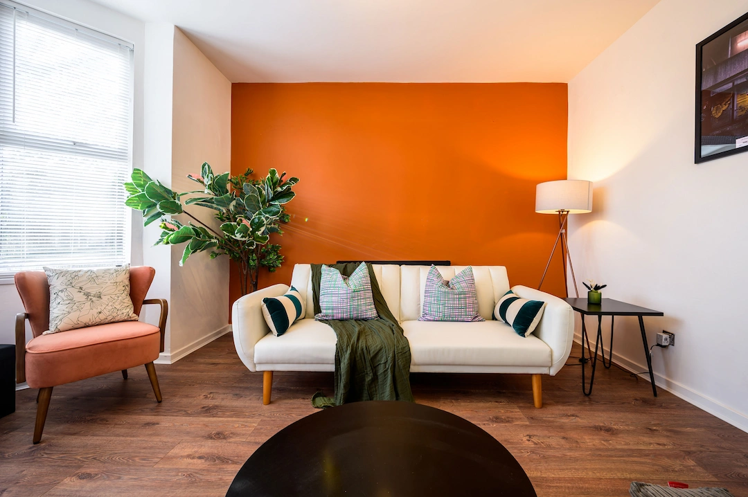 After: St John's living room styled with orange accent wall, white sofa, plants, and premium finishes